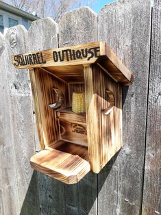 a wooden box that has some sort of shelf inside of it on the side of a fence