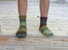 the legs of a person standing on a wooden platform wearing socks with multicolored stripes