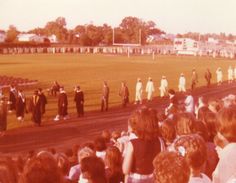 a group of people standing on top of a lush green field next to a soccer field