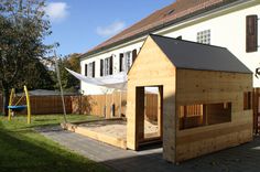 a dog house built into the side of a backyard with a play area in front