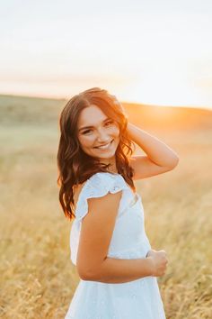 a girl in a white dress is smiling and standing in the middle of a field