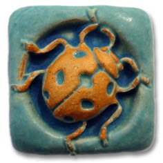 a ceramic tile with an orange and blue bug on it