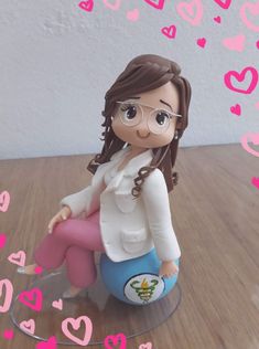 a small figurine sitting on top of a blue ball with pink hearts around it