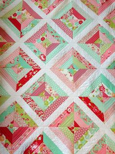 a pink and green patchwork quilt on display