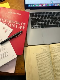 a laptop computer sitting on top of a desk next to a pile of books and papers