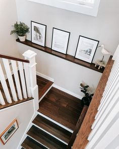 stairs leading up to the second floor in a home with pictures on the wall and below them