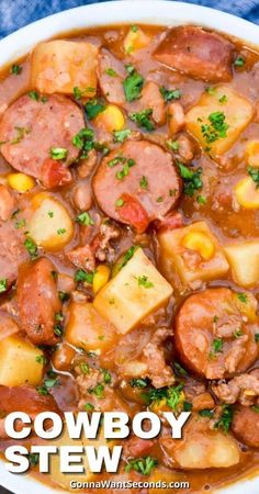 a white bowl filled with stew and potatoes on top of a blue cloth next to a spoon