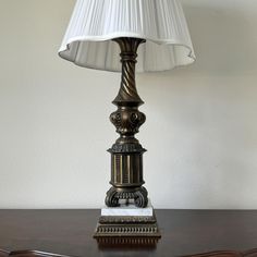 a lamp that is on top of a wooden table with a white shade over it