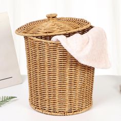 a wicker laundry basket with a pink towel on top and a white wall in the background