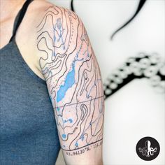 a woman's arm with a blue and white map tattoo on the left arm