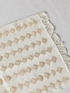 a beige and white rug with fringes on the bottom is laying on a table