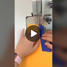 a woman is using a sewing machine to sew on something yellow and blue paper