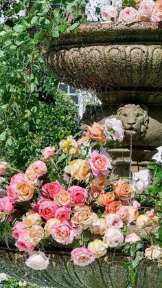 there are many flowers in the planter by the fountain