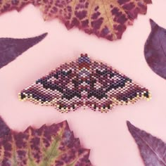 a beaded brooch sitting on top of leaves