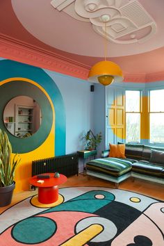 a living room filled with lots of furniture and colorful decor on the walls, along with a round rug