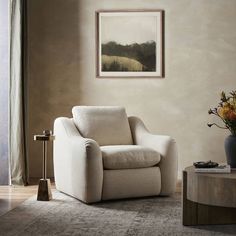 a living room with a chair, table and painting on the wall in it's corner