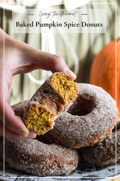 a person holding a piece of pumpkin spice doughnuts