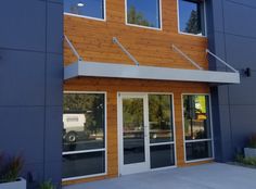 the front entrance of a building with glass doors and wood paneling on the side