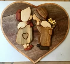 a wooden heart shaped plaque with two people kissing in the shape of a man and woman