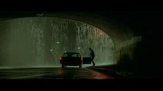 a car driving through a tunnel with water shooting from it's side and people standing next to it