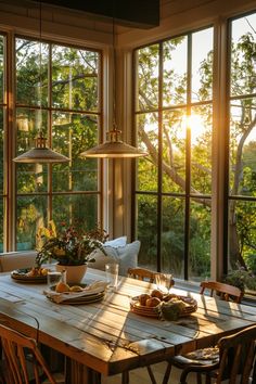 a dining room table with plates and bowls on it in front of large windows overlooking trees