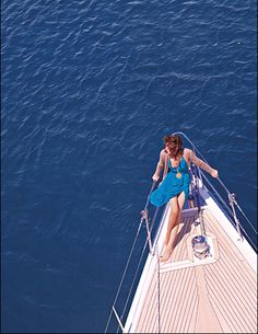 a woman sitting on top of a boat in the ocean