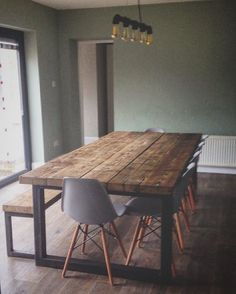 a wooden table sitting in the middle of a room next to two chairs and a window