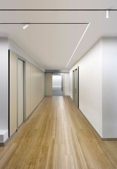 an empty room with white walls and wooden floors is seen in this image from the hallway