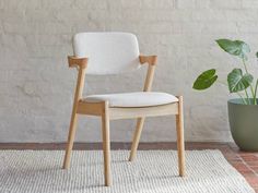 a white chair sitting on top of a rug next to a potted plant