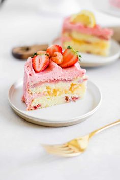 a piece of cake with pink frosting and strawberries is on a white plate