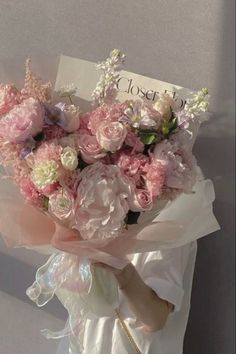 a bouquet of pink and white flowers is held by a woman's hand with a sign that says closer to heaven