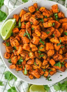 mexican sweet potatoes in a white bowl with cilantro and lime on the side