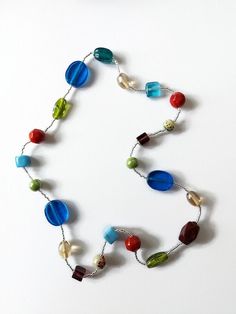 a necklace made with glass beads and multicolored beads is displayed on a white surface