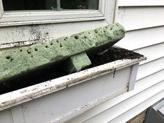 an old green bench sitting on top of a window sill in front of a house