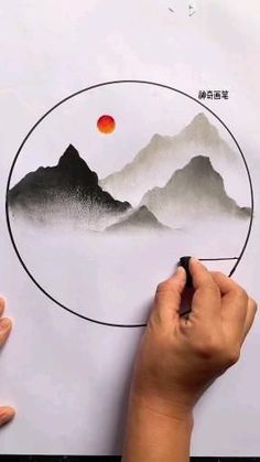 someone is drawing a landscape with mountains in the background and an orange sun at the top