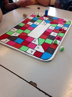 a close up of a board game on a table with people sitting at the table