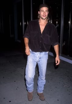 a man in jeans and a hat is standing on the sidewalk