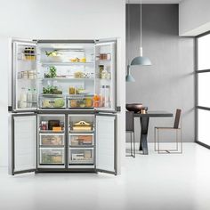 an open refrigerator with its doors wide open in a kitchen area next to a dining room table