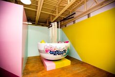 a large bowl sitting on top of a wooden floor next to a yellow and pink wall