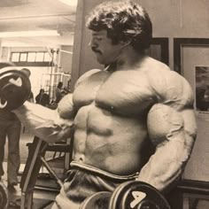 a man in a bodybuilding suit holding two dumbbells while standing next to another man