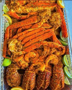 cooked lobsters and crab legs with lemon wedges in a glass dish on a table