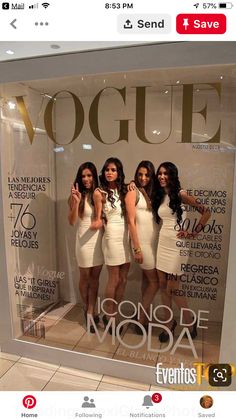 three women in white dresses are standing behind a window display with the words voque on it