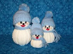 three small stuffed animals wearing knitted hats and scarves on a blue background with snowflakes