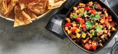 a bowl of black beans and corn with tortilla chips next to it on a table