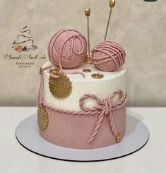 a pink and white cake decorated with balls of yarn