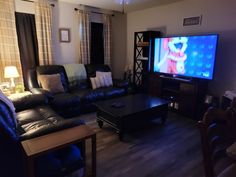 a living room filled with furniture and a flat screen tv on top of a wooden table