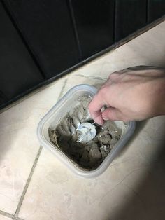 a person is scooping ice cream into a container on the floor with their hand