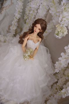 a barbie doll dressed in a white wedding dress and holding a bouquet with her hand