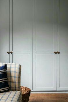 a couch sitting in front of some white cupboards with blue and white plaid pillows