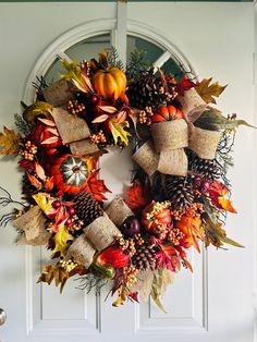 a wreath with autumn leaves and pumpkins hanging on the front door to welcome guests